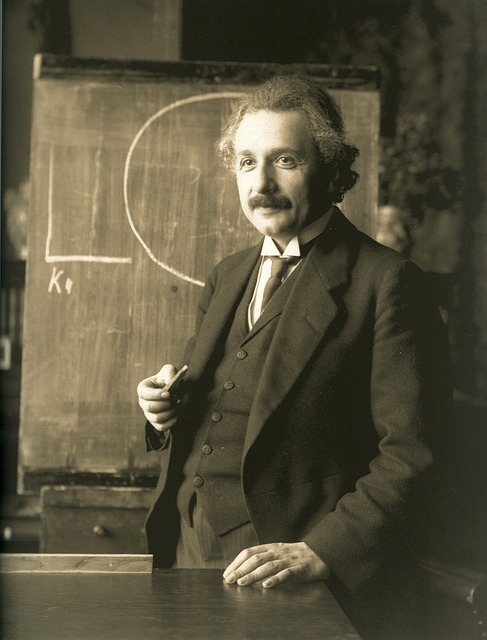 picture of Albert Einstein standing in front of a chalk board.