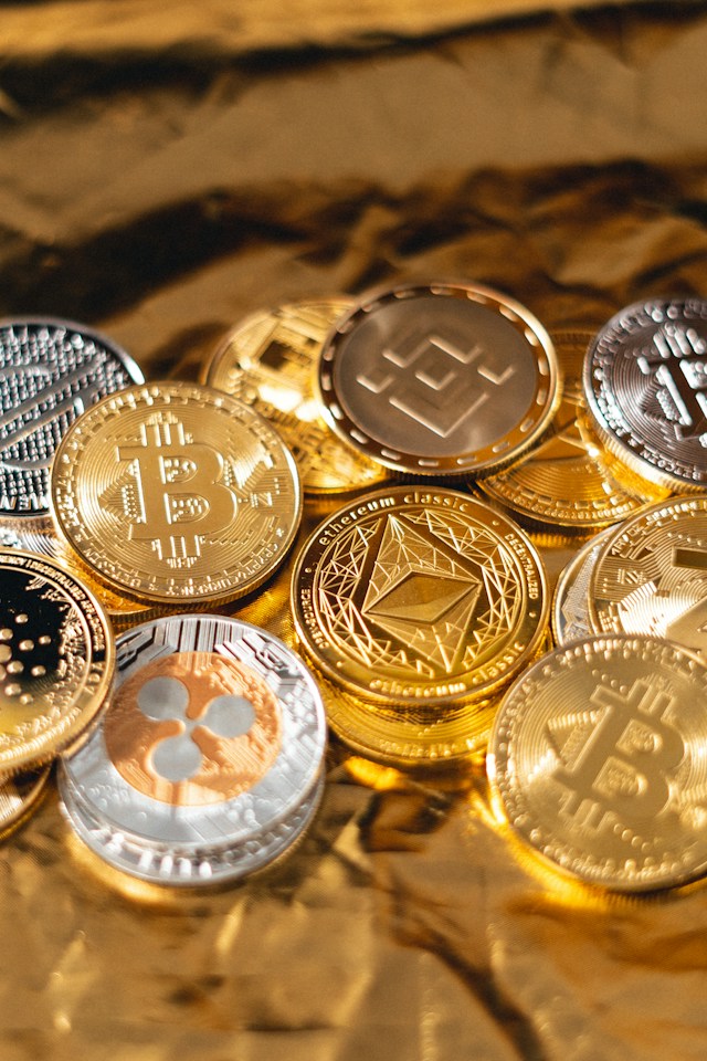 A bunch of gold / silver coins with different crypto currency logos on the coins.