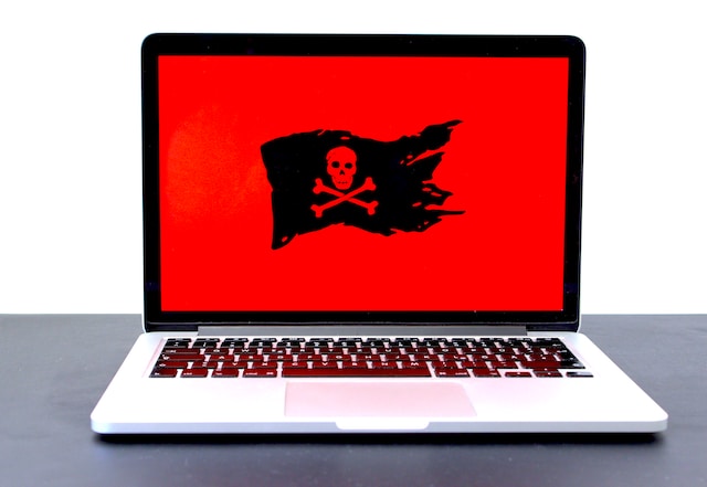 Laptop computer with the red with black flag with crossbones on the screen.