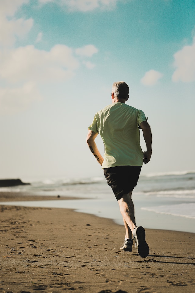 man on a beach running away from the camera along the shoreline.