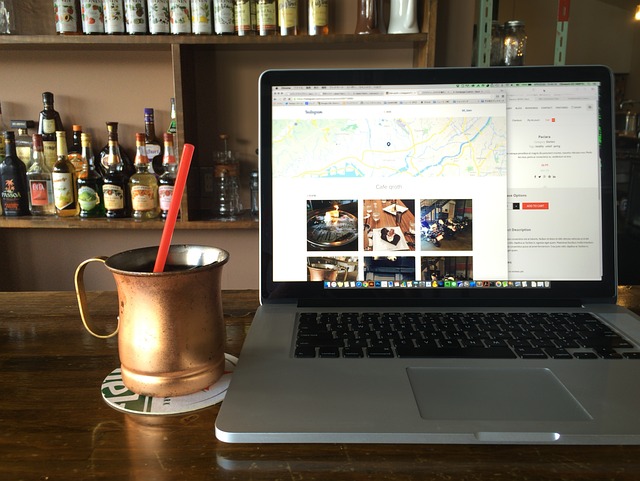Inside a coffee shop, at a counter is a mug of coffee or some other drink and a laptop with the screen on a map.