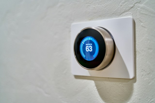 This is a close up of a wall with a Nest smart home thermostat. It is set to 63 degrees.